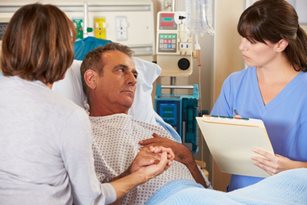 Family and nurse gathered around dad in hospital bed