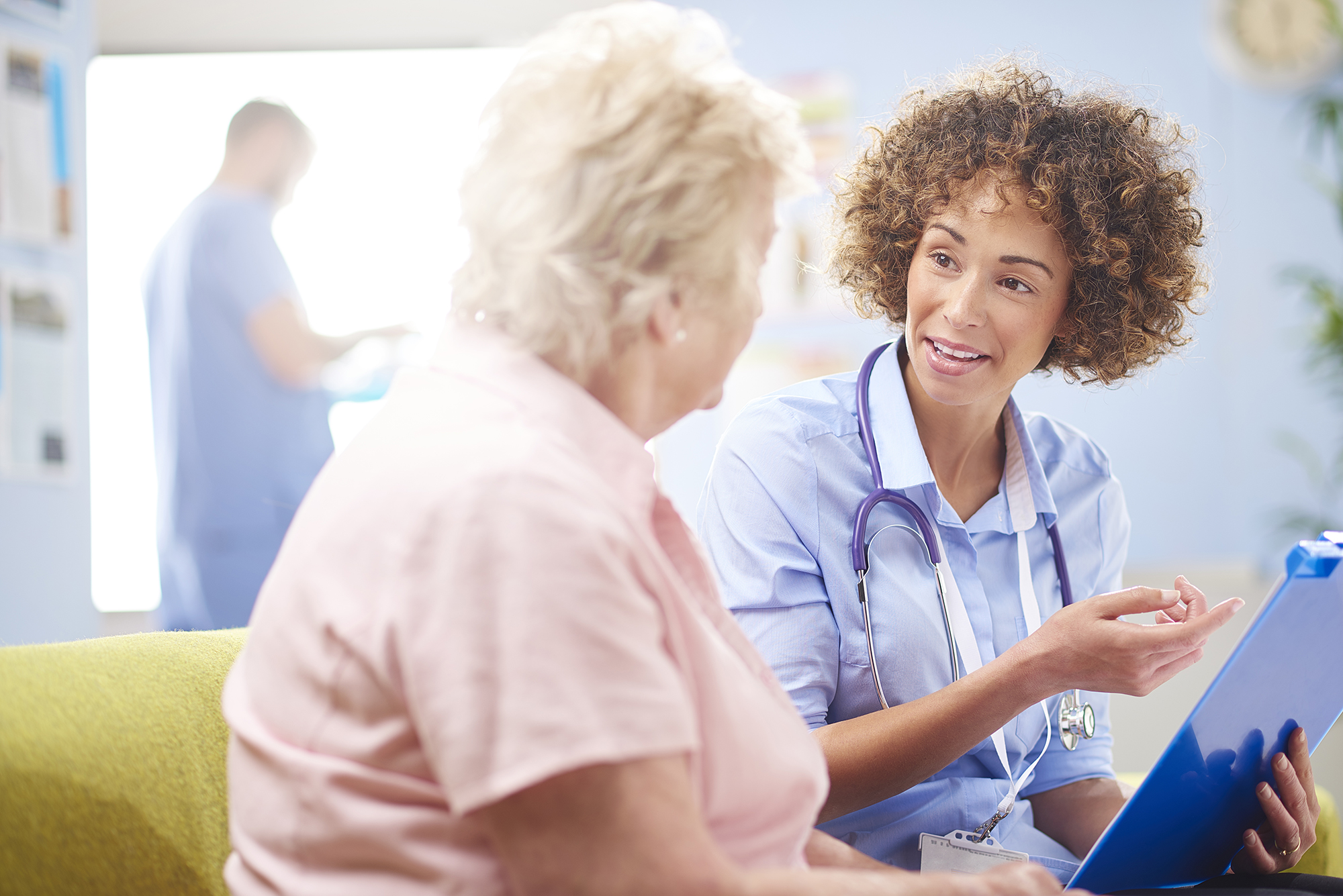 Medical doctor or nurse talking to an older woman patient