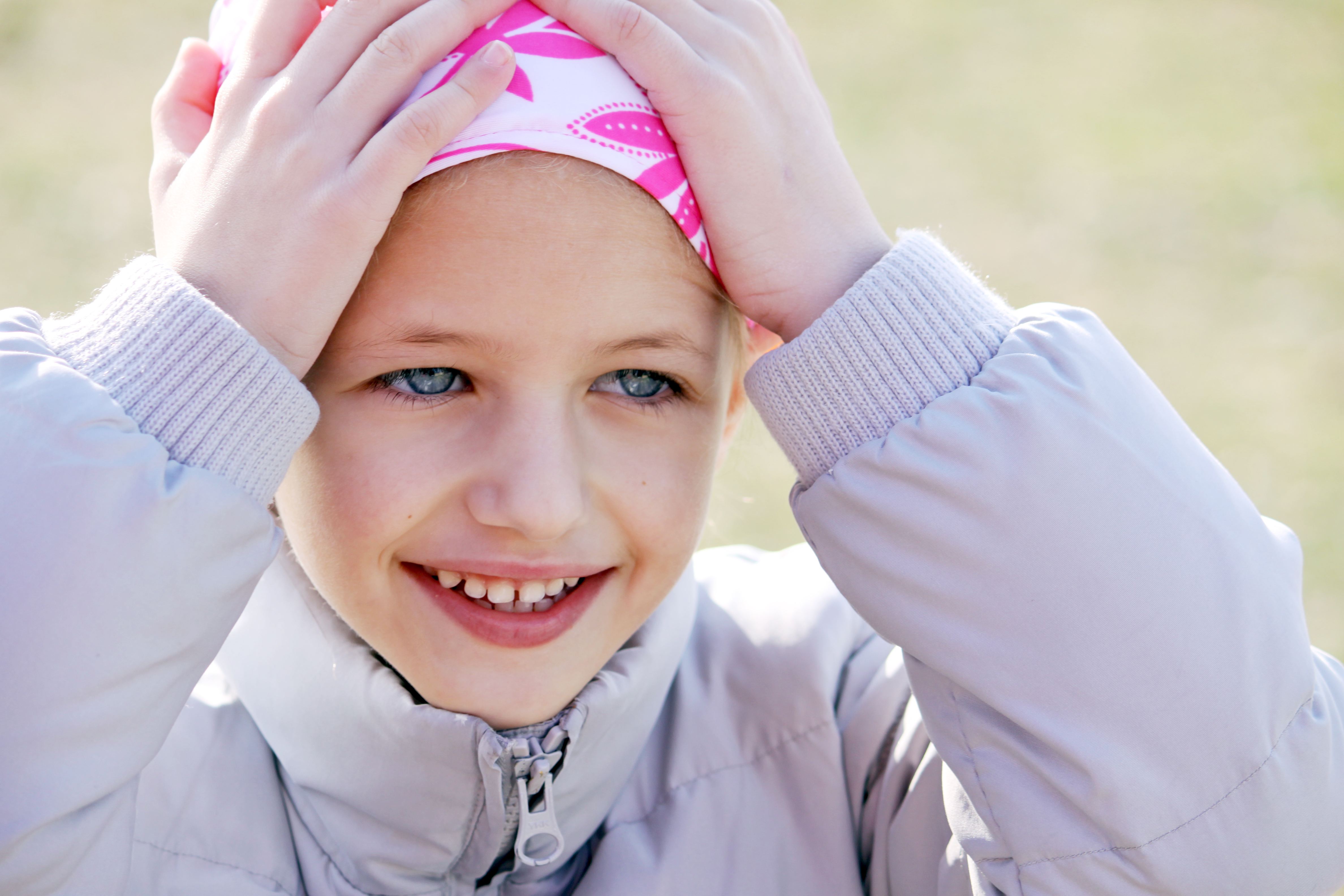A smiling girl holding her bandana, which covers her bald head