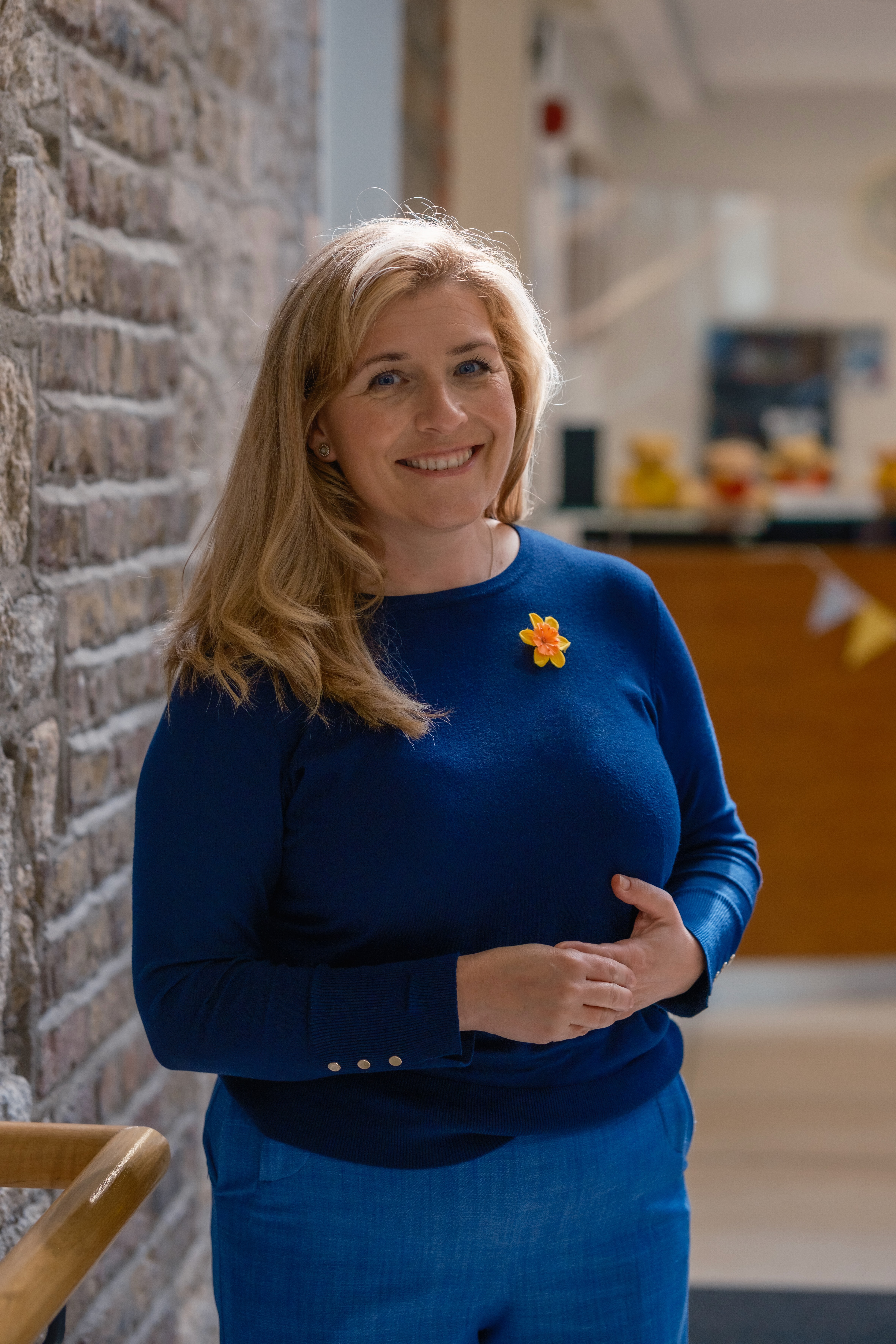 Blonde woman in blue top looking directly to camera