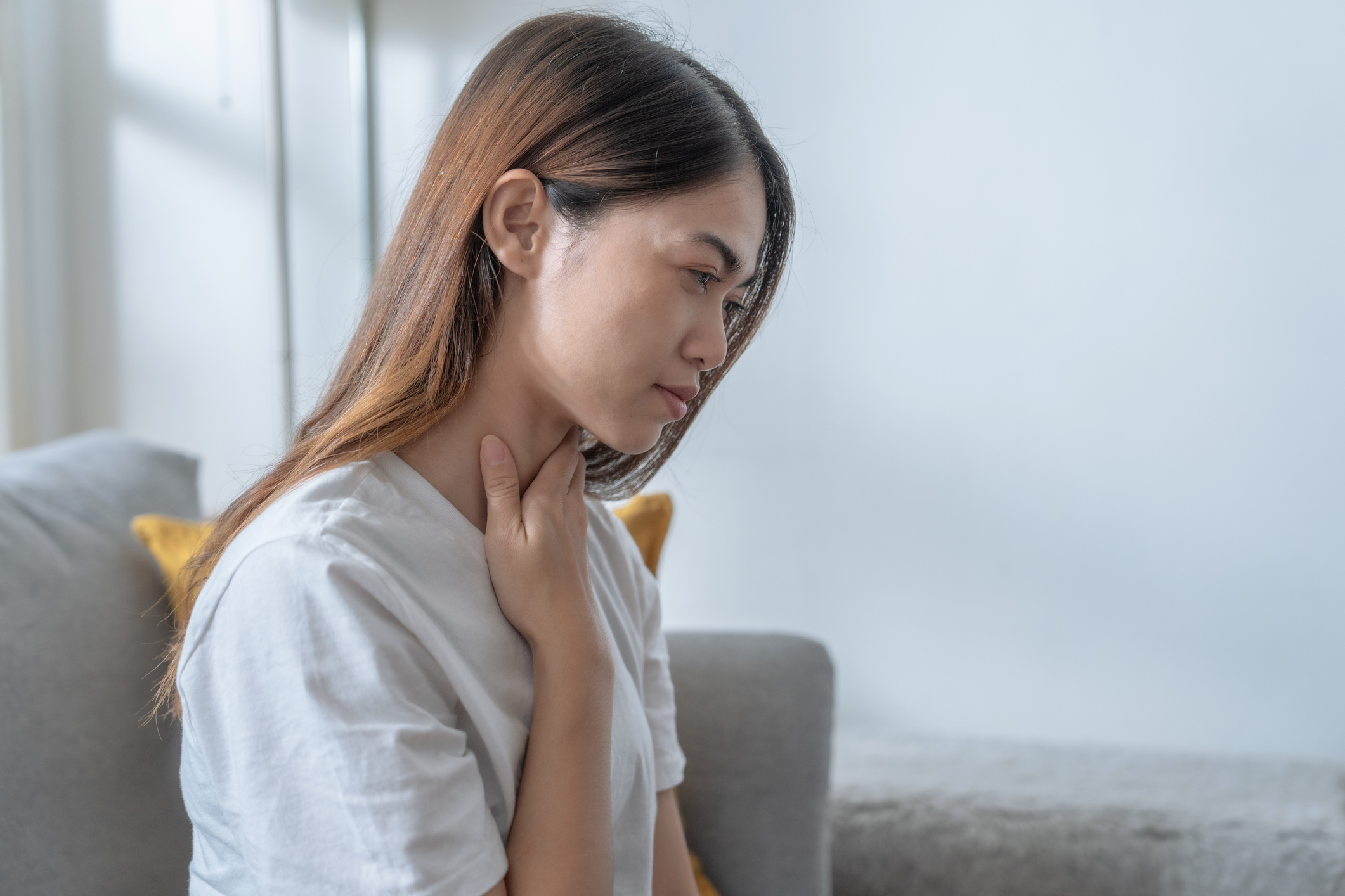 Lady feeling her throat and looking worried