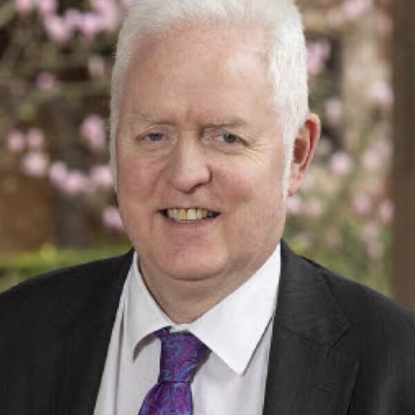 Man smiling to camera wearing suit and purple tie