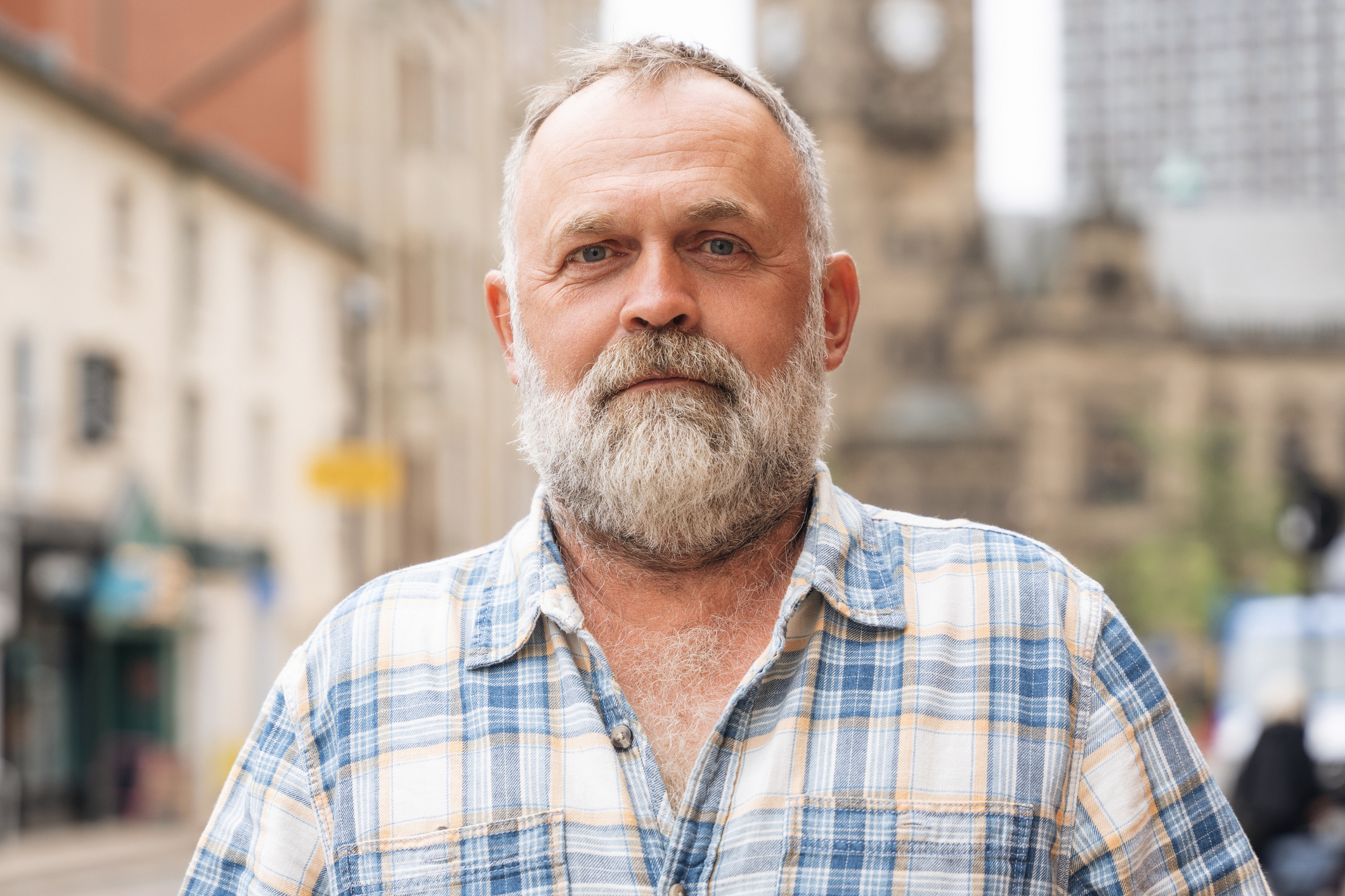Middle-aged white man with beard eyes to camera on city street