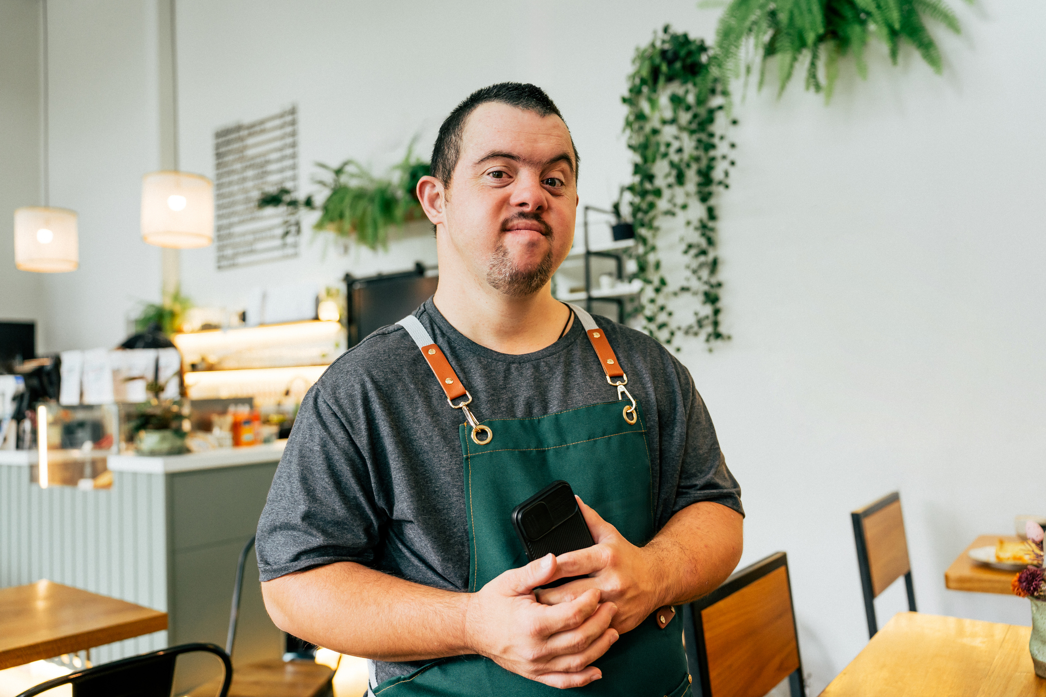 White man in 30s w Down syndrome working in cafe eyes to camera