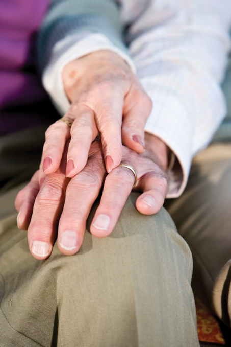 A woman's holding her hand over a man's hand in a gesture of comfort and support