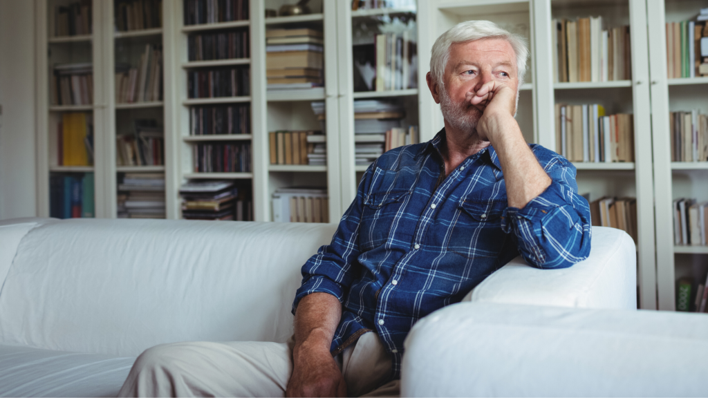 older man sitting on a sofa, looking thoughtful