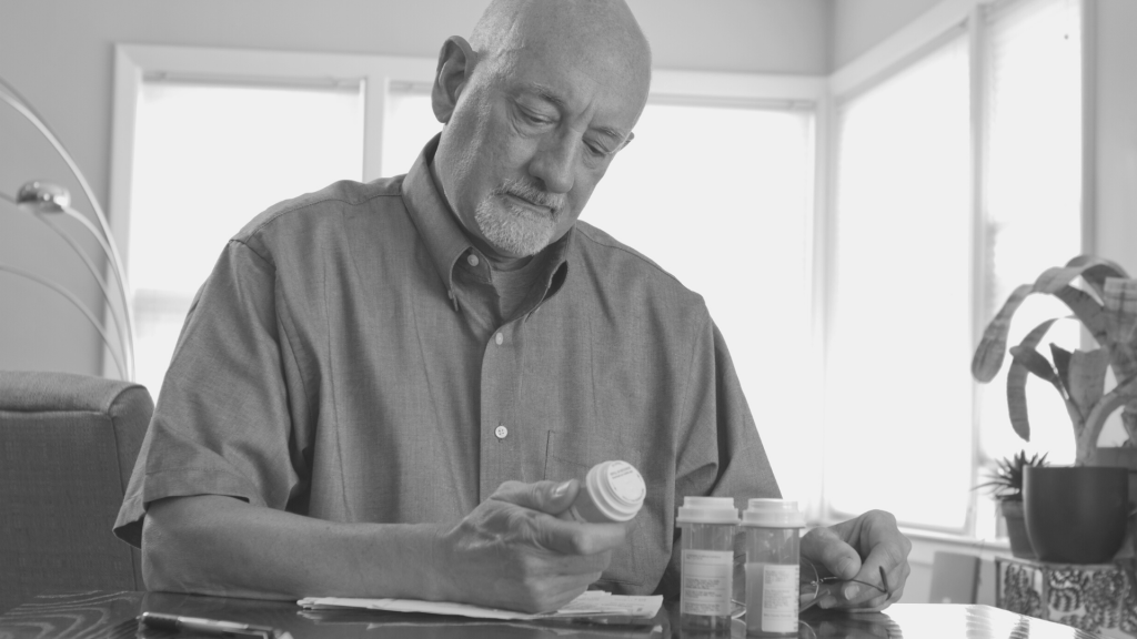 older man looking at medication