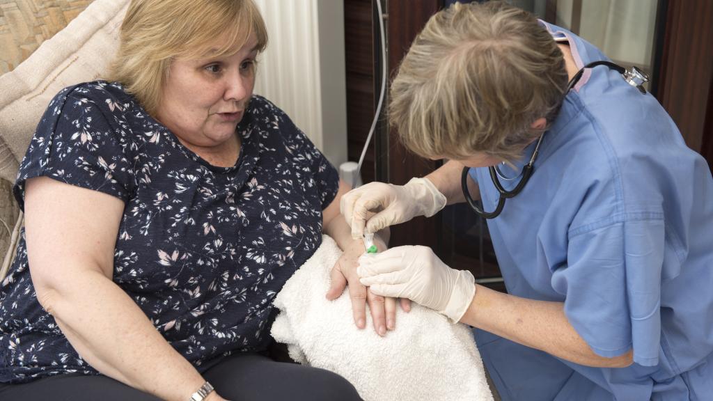 Nurse putting an IV needle into a patient's hand