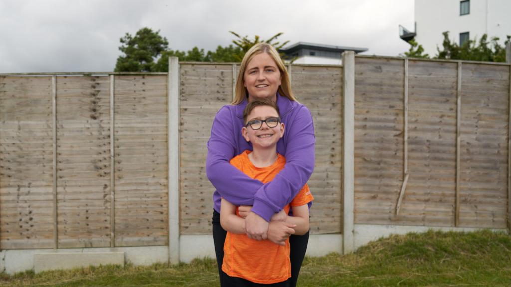Caiden and his Mam hug in their back garden