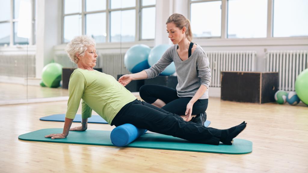 Older woman exercising beside her doctor