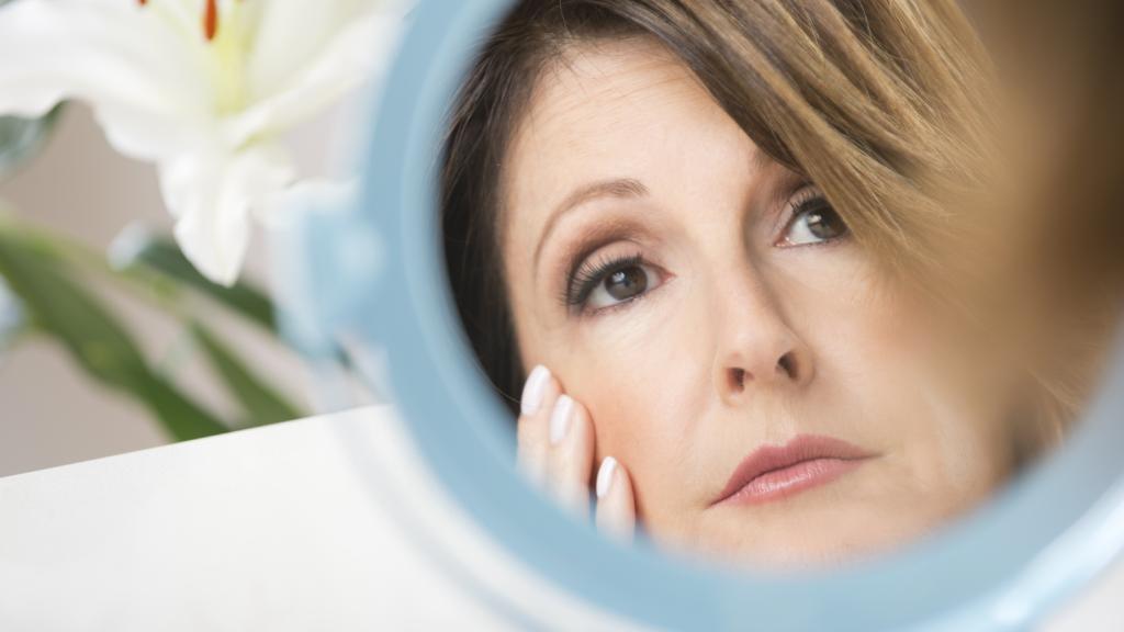 Worried woman looking at her skin in the mirror
