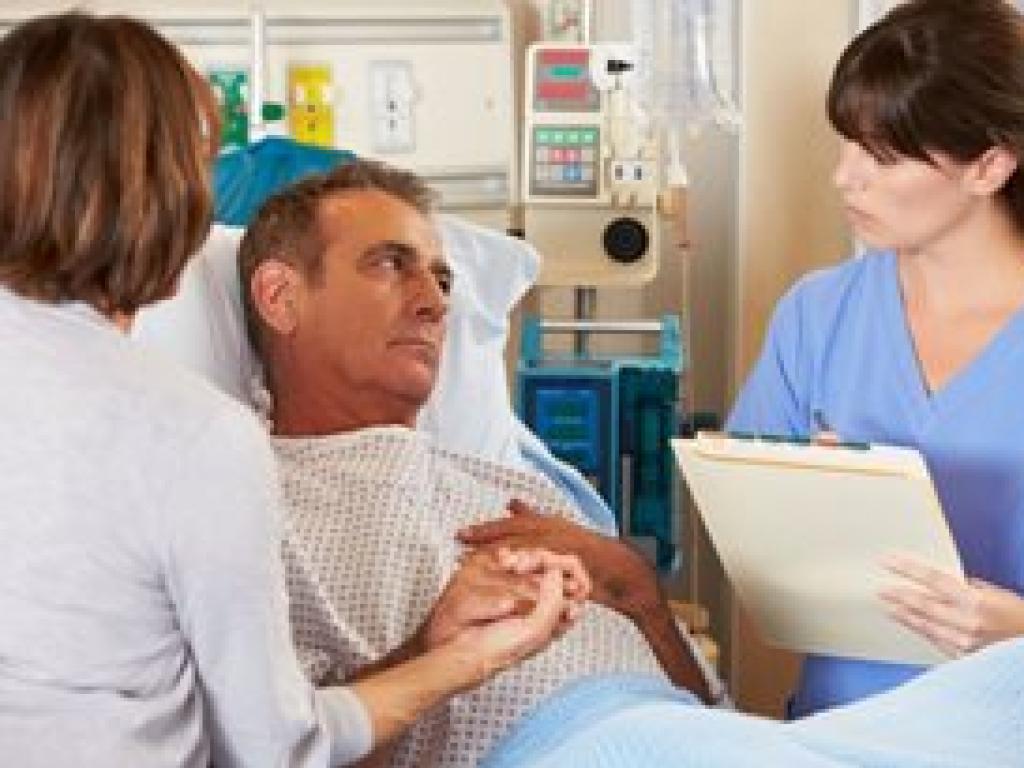 Family and nurse gathered around dad in hospital bed