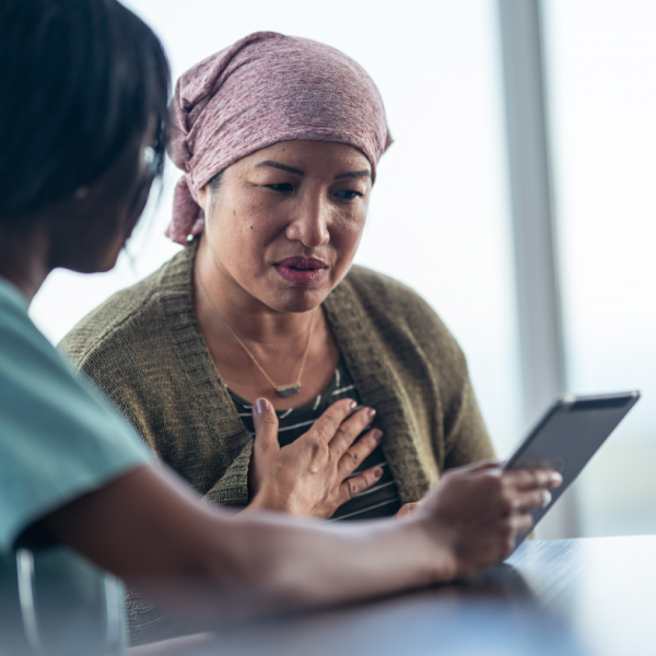 post-chemo older Asian woman discussing options with black female nurse
