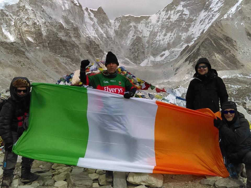 Trekkers holding an Irish flag on a mountain