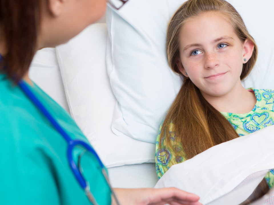 A girl in a hospital bed with a nurse