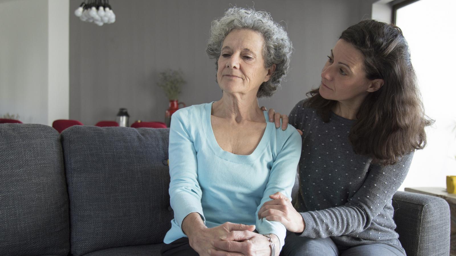 Younger woman consoling older woman on couch