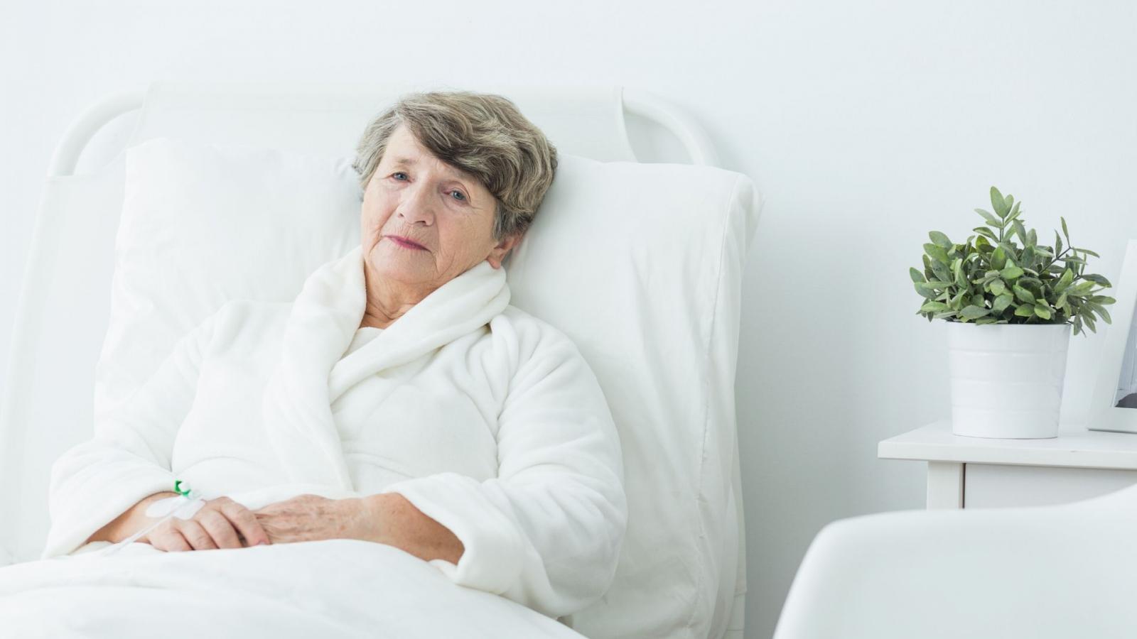 Woman wearing a white towelling robe lying in a hospital bed