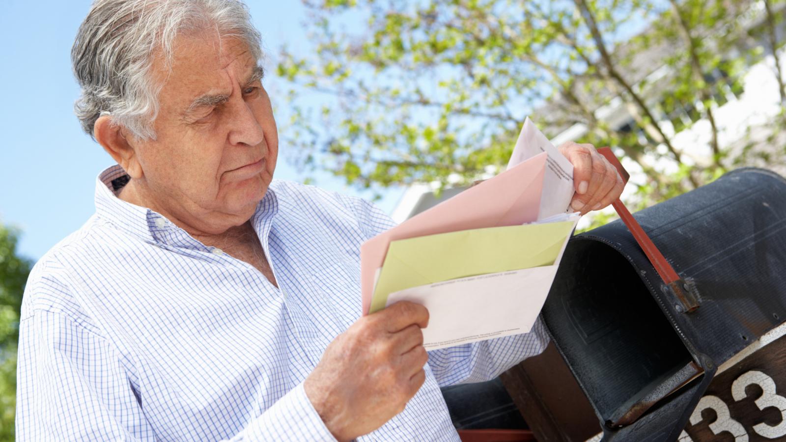 Older man looking worriedly at his post