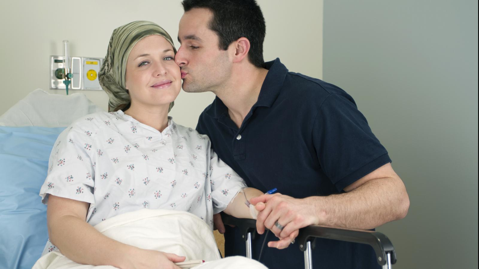 Woman in a hospital bed getting kissed by her husband