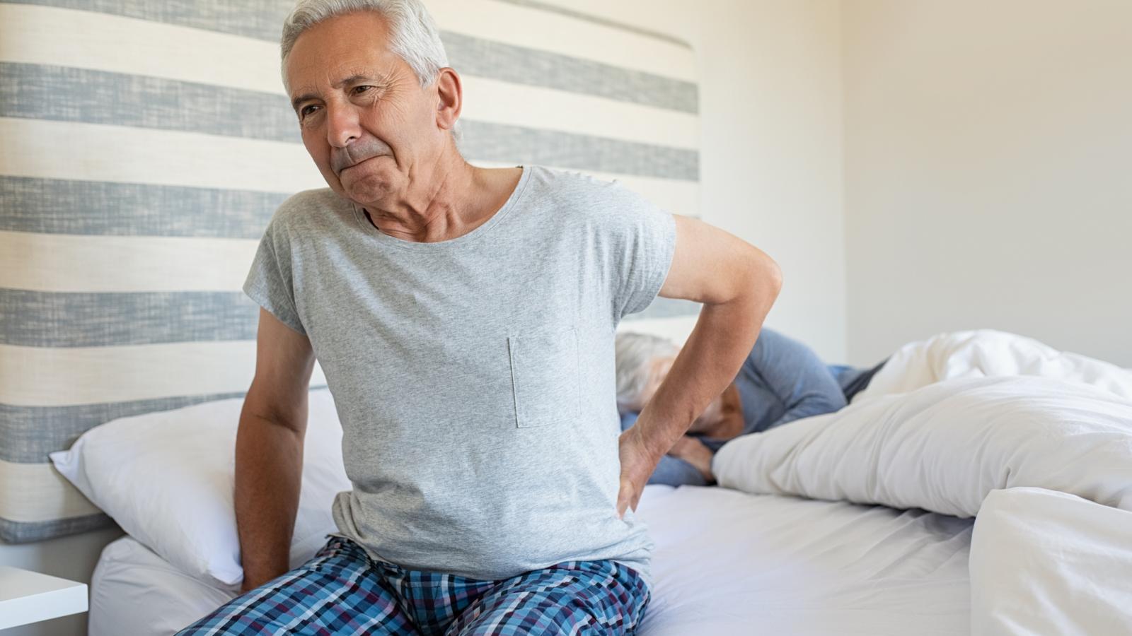Older man in pain sitting in bed