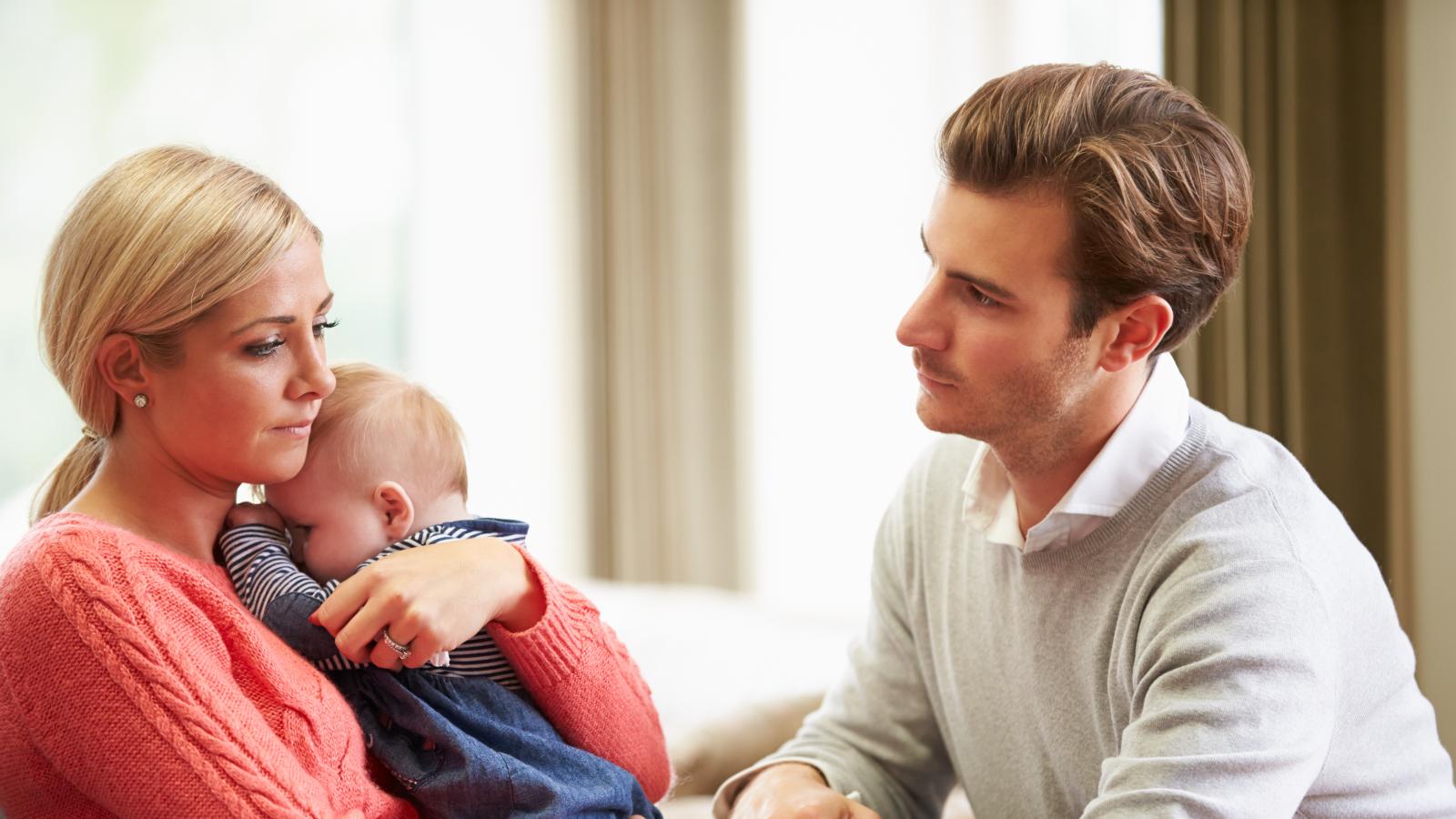 Parents looking sad hugging their baby
