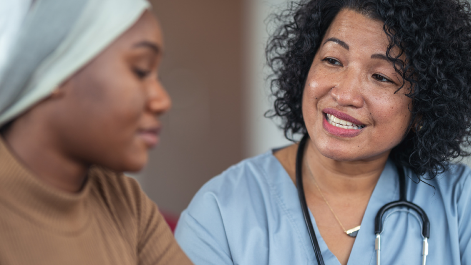 post-chemo younger black breast cancer patient talking to female nurse