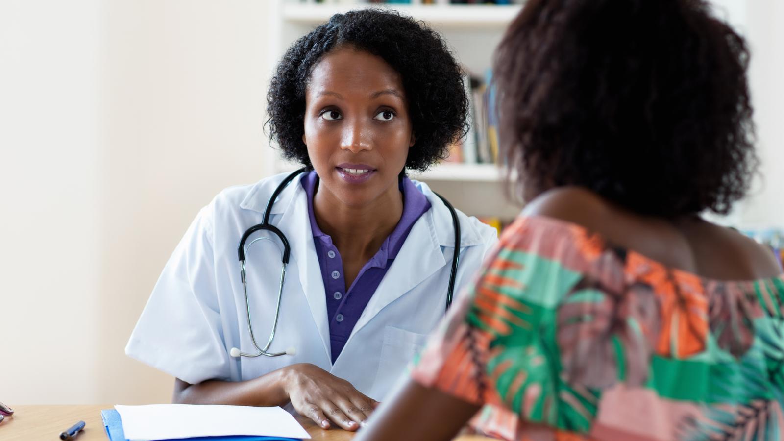 A black female doctor talking to a black female patient