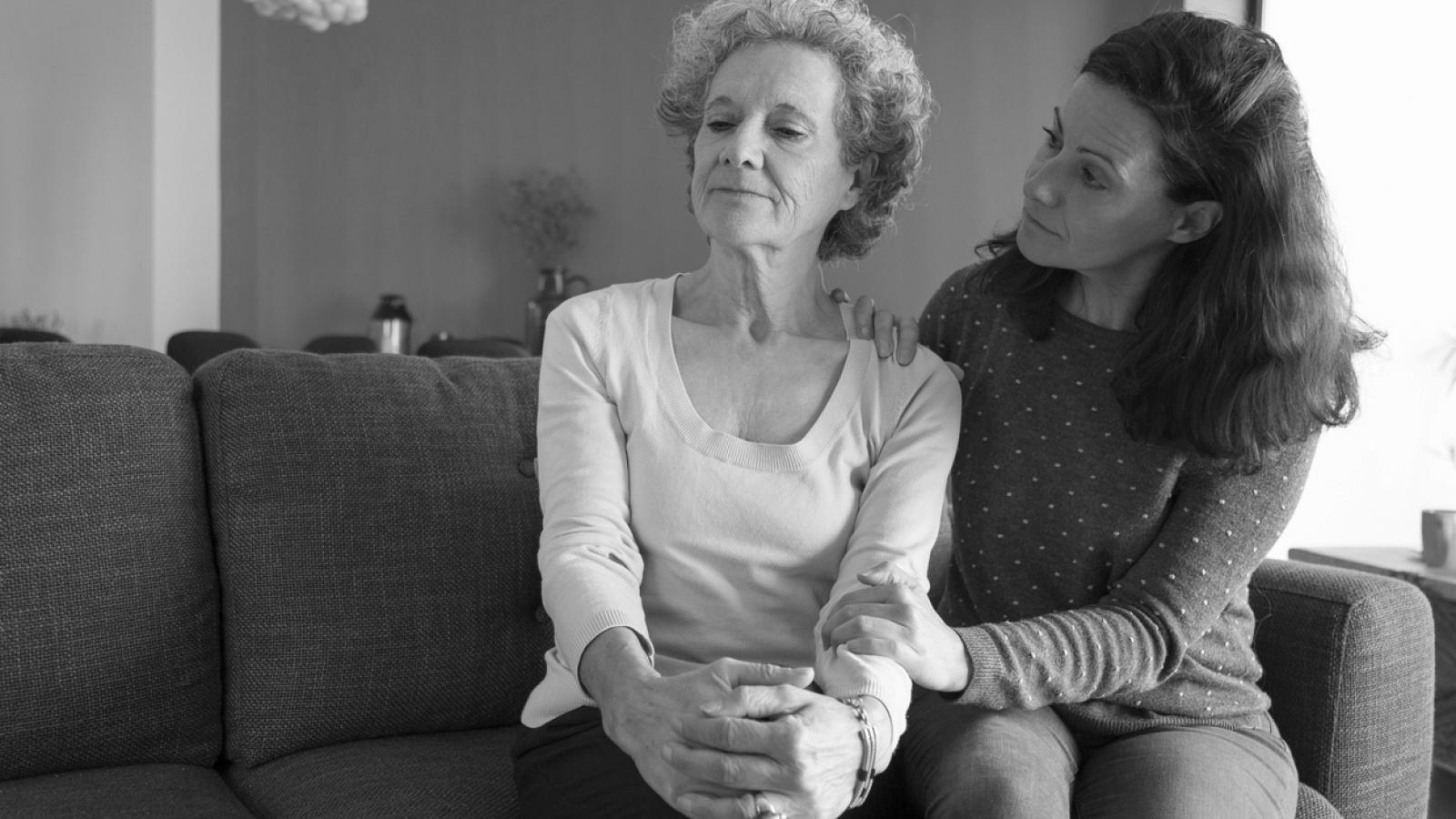 Younger woman consoling older woman on couch