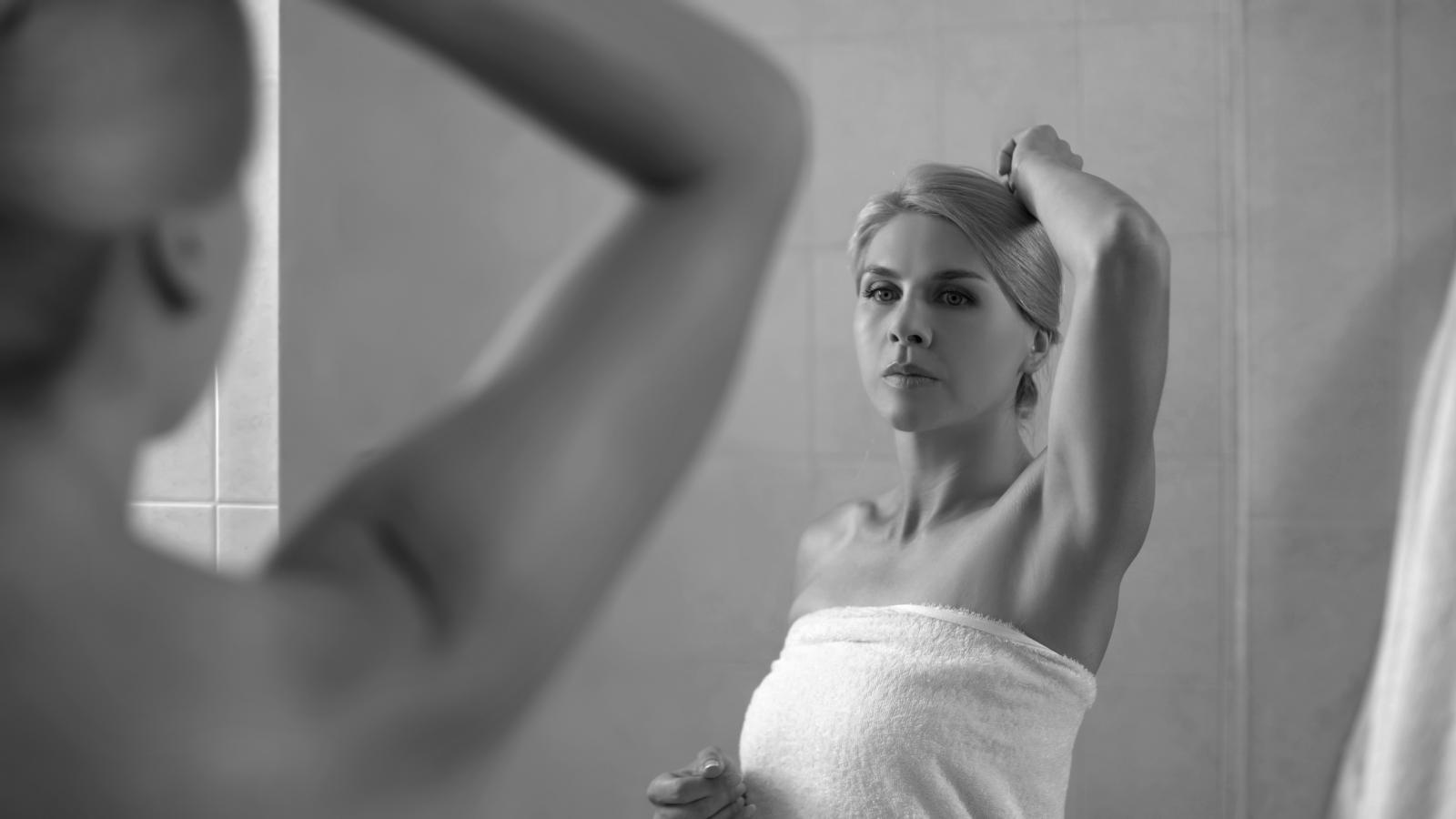 Woman looking at her underarm in the mirror