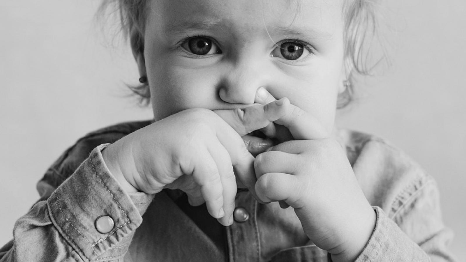 Little girl holding her mouth