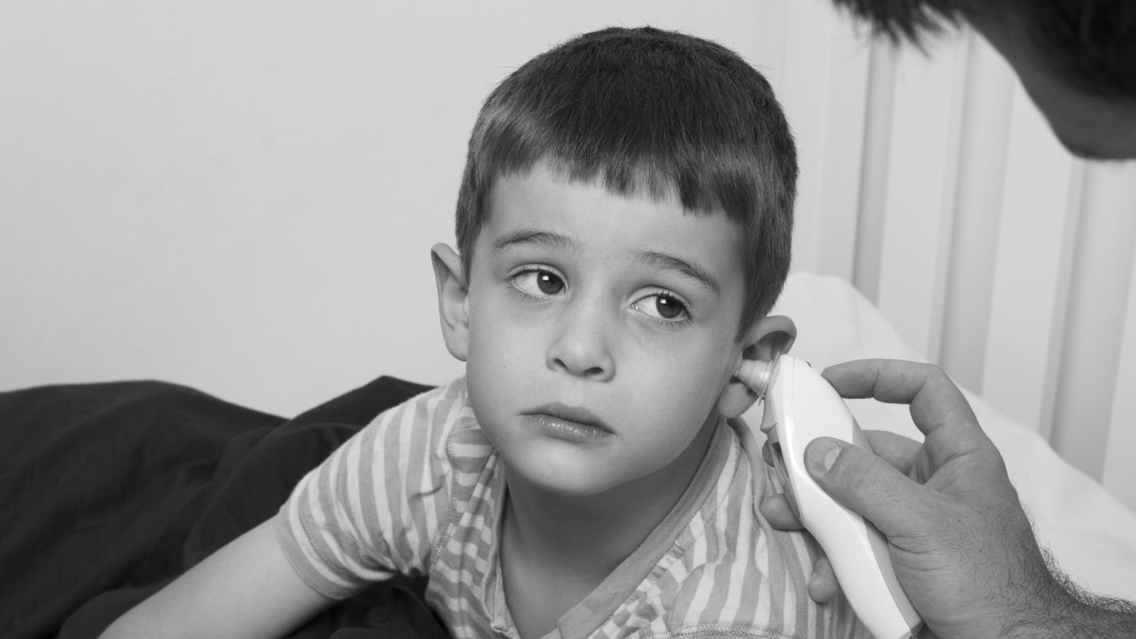 A boy gets his temperature taken with an ear thermometer